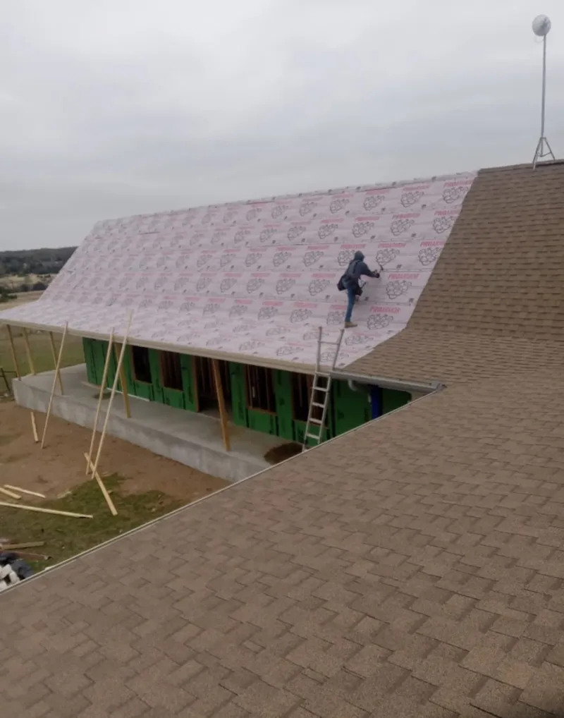 Worker preparing underlayment for a metal roof installation in Clanton